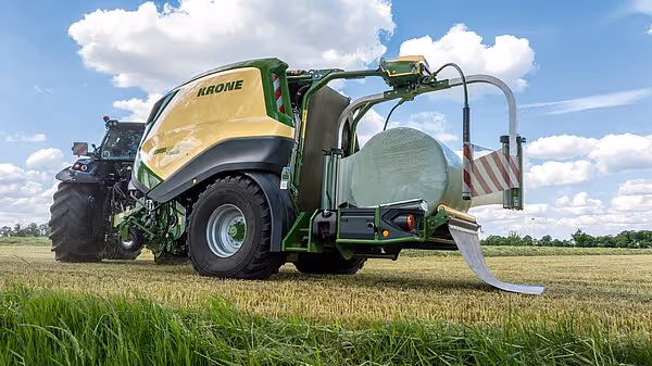 KRONE CombiPack HDP rundballpresse på åker med blå himmel og hvite skyer i bakgrunnen.