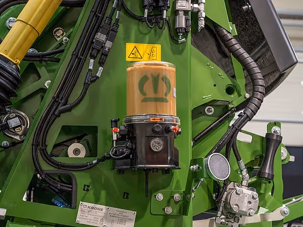 Hydraulisk motor med smøresystem og sikkerhetsskilt montert på grønn maskinramme.