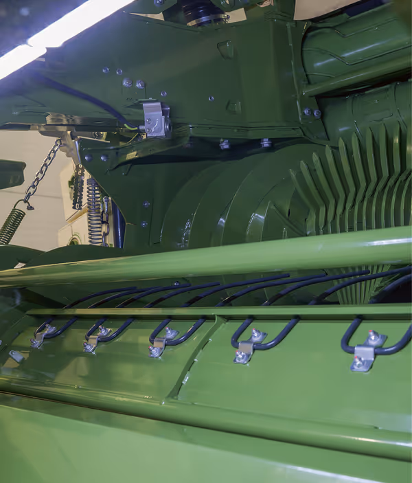 Nærbilde av indre mekanismer på KRONE CombiPack HDP, viser grønne metallkomponenter og hydrauliske systemer. Detaljert visning av maskinens tekniske deler og monteringsbolter.