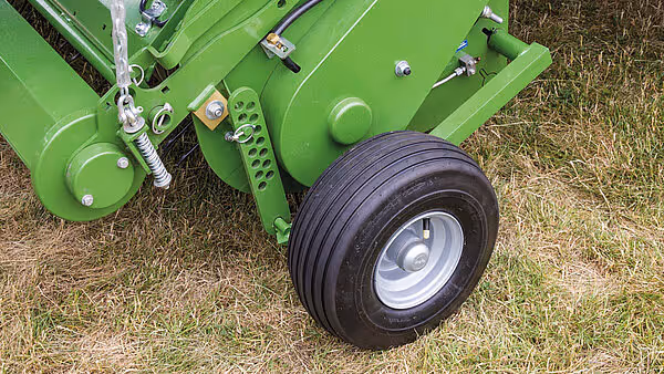 Nærbilde av hjul og understell på grønn KRONE Comprima rundballpresse.