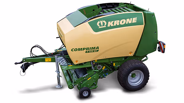 KRONE Comprima rundballpresse vist fra siden, en grønn og gul landbruksmaskin for pressing av høy og halm til rundaller.