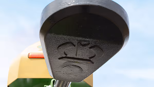 Nærbilde av en svart plastkomponent med preget KRONE-logo på EasyWrap 150 ballpressen.