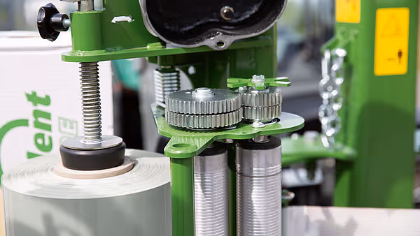 Detaljbilde av tannhjulmekanismen og justeringsskruen på KRONE EasyWrap 150 ballpressens indre deler.