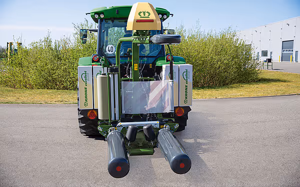 Bakside av KRONE EasyWrap 150 rundballepresser montert på traktor, med synlige filmruller og hydrauliske sylindre.
