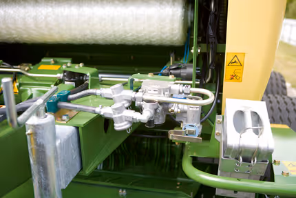 Detaljbilde av Krone Fortima rundballpreses innvendige mekanisme med binding- og kuttesystem synlig.