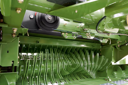 Krone Fortima rundballpresse i arbeid på åker med ferdig presset rundball som ruller ut bak maskinen.