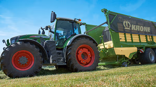 KRONE MX pressemaskin montert på traktor under feltarbeid med både forkutter og pressemekanisme synlige.