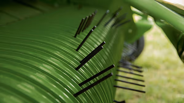 Nærbilde av rotorbørsten på KRONE MX med sorte reiver/tenger som strekker seg radielt ut fra den grønne trommelen.