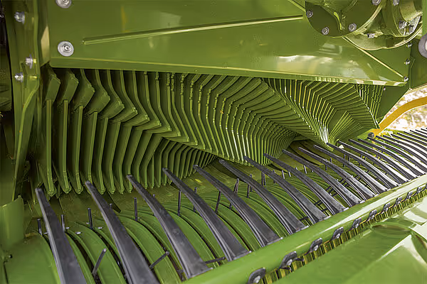 Åpen høstmaskin som viser det indre oppbygget med grønne siler og sorte rister for sortering av høyet.