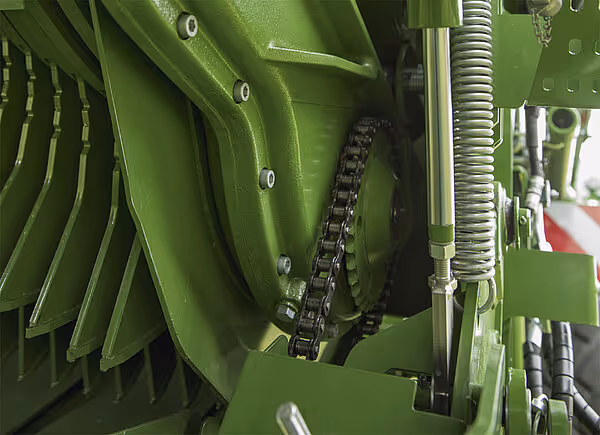 Nærbilde av KRONE MX sine mekaniske komponenter med sort kjede og grønne metallplater.