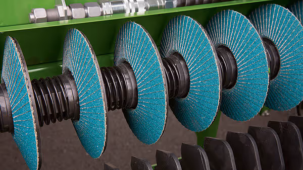 Rekke av turkoise slipeskiver med svart senterdel montert parallelt på rotoren av KRONE MX-serien.