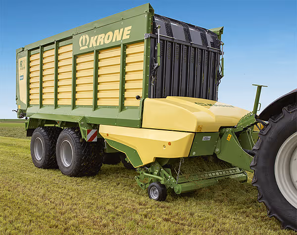 Sidebilde av grønn og gul Krone MX silofyll-vogn med doble bakakslinger og åpne sidevegger.
