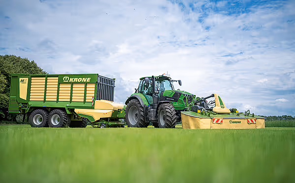 KRONE MX rottefôrer trukket av grønn traktor med silasevogn i eng, tilhørende høstsystem for grassilage.