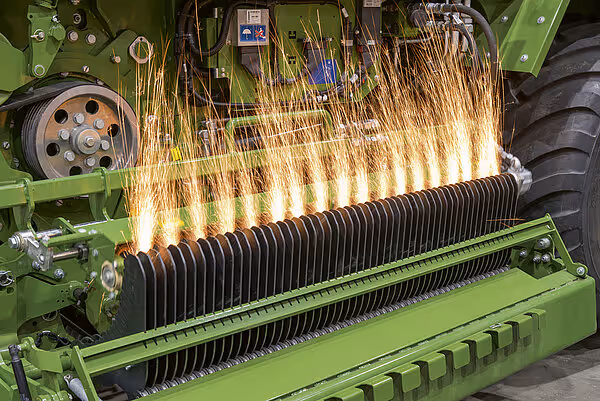 Rotorkutter i aksjon med gnister som spruter fra knivene som hugger halm under harvesting.