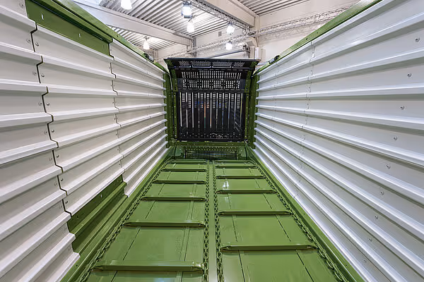 Innvendig av KRONE RX hakkevogn med grønt stålkammer og lukkede sideporter for silering av høy.