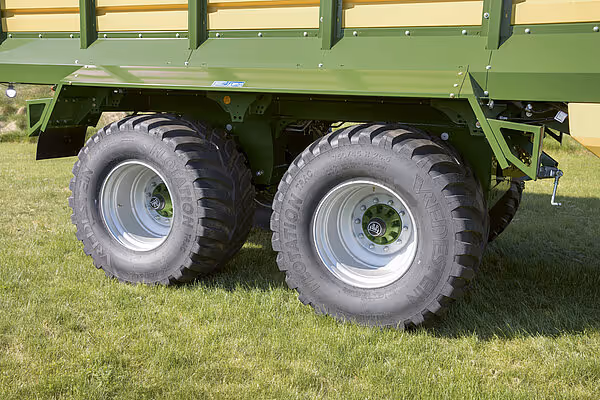 Nærbilde av bakakselen på en KRONE RX hengervogn med to store landbruksdekk montert på aluminiumsfelger.