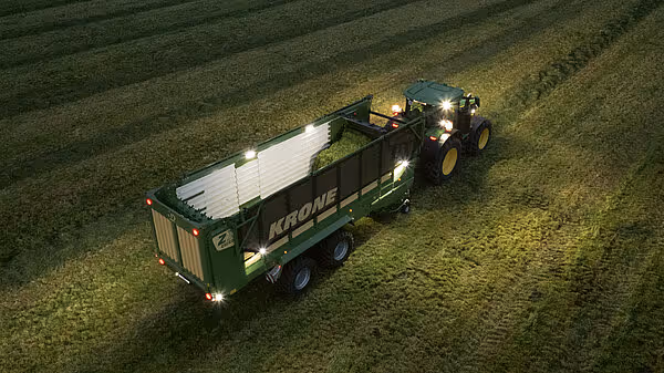 Luftfoto av en KRONE RX vogn lastet med høy, trukket av traktor ved kveldstid.