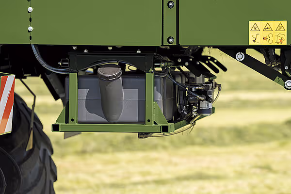 Underside av KRONE RX høstevogn med grønn ramme, sort hydraulisk sylinder og sorte mekaniske komponenter mot grønn bakgrunn.