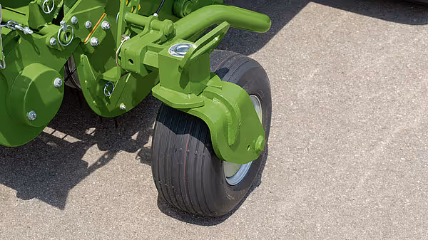 Hjul og understell på en grønn KRONE rundballpresse med store landbrukshjul for transport på åker.