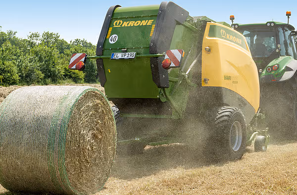 KRONE VariPack rundballpresse slipper ferdig innpakket rundball med grønt nett på stubbeåker.