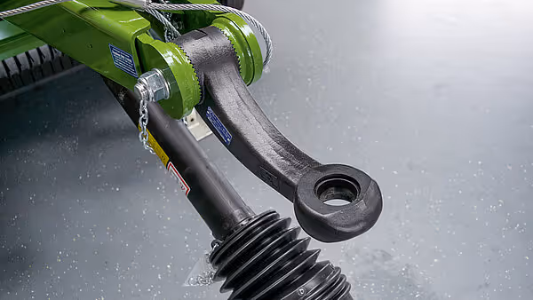 Detaljbilde av hydraulisk sylinder og trekkmekanisme på landbruksmaskinen.