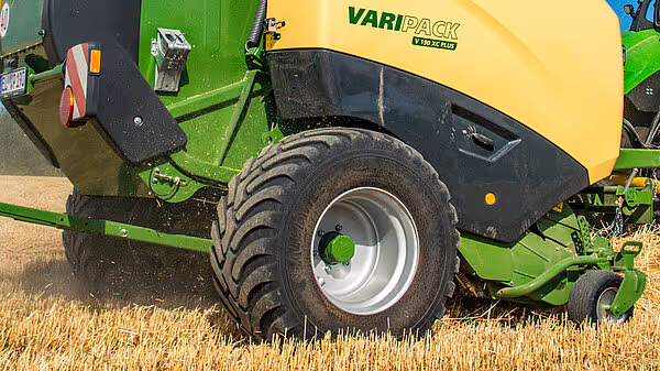 Nærbilde av hjul og understell på Krone Varipack Plus under arbeid på kornåker.