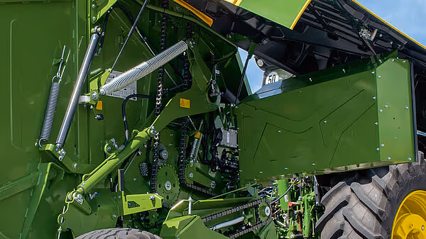 Detaljbilde av hydrauliske komponenter og mekaniske deler på Krone Varipack Plus rundballpresse. Viser grønne hydraulikksylindre og tekniske forbindelser.