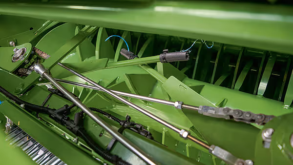 Innvendige komponenter i preskammeret på Krone Varipack Plus rundballpresse. Viser oppsamlingsmekanismer og rullevalser for ballforming.