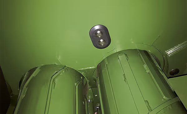 LED arbeidsbelysning montert på taket av en grønn KRONE VariPack Plus rundballpresse. Lyset er designet for å belyse arbeidsområdet under kveldsoperasjoner.