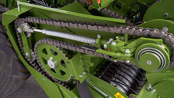 Kjededrift og fjærsystem på KRONE VariPack Plus rundballepresse med grønt chassi og drivmekanisme.