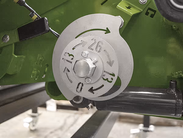 Justeringsskive med tallmarkering fra 0-26 for innstilling av bindetrådens posisjon på rundballpressen.