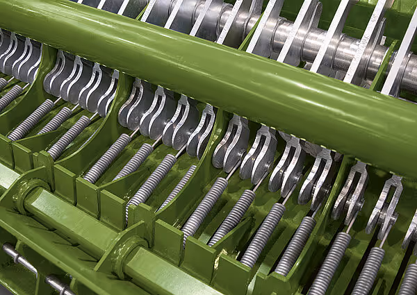 Detaljbilde av knivsettet i KRONE Varipack Pro som viser rekkene med skarpe kniver og fjærer for kutting av fôr.