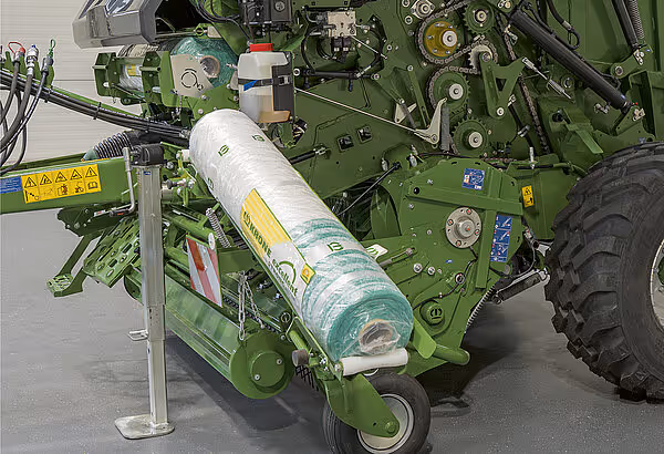 KRONE VariPack Pro rundballpresse med hvit plastballefolie montert i foliesystem. Maskinen står på betonggulv i verksted eller lager.