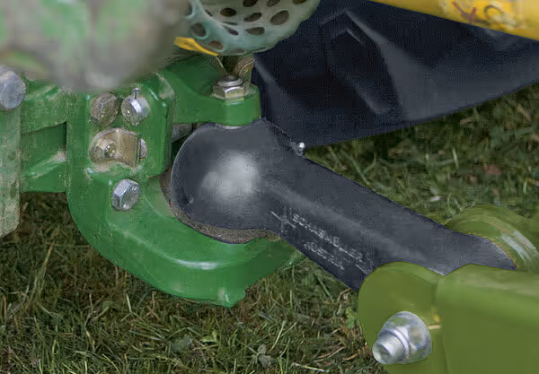 Nærbilde av trekkøye og hydrauliske tilkoblinger på KRONE Varipack rundballpresse. Utstyret viser grønne metallkomponenter og sorte hydraulikkslanger.