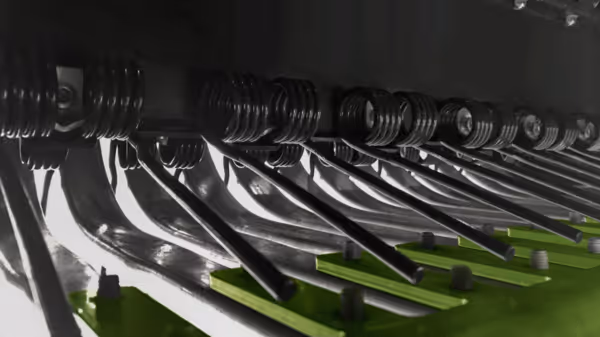 Detaljbilde av pick-up enheten på en Krone VariPack Pro rundballpresse med metalliske tinner og grønn ramme.