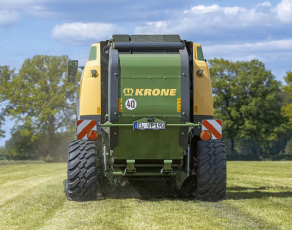Bakside av KRONE VariPack Pro rundballpresse i arbeid på eng, med synlig ballkammer og registreringsnummer.