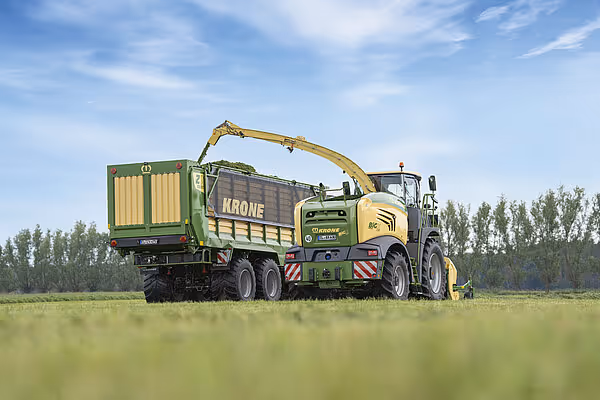 Krone ZX høstingsvogn med hydraulisk grep lastes med maursylage fra en selfølger, fotografert fra siden på åpent jorde.