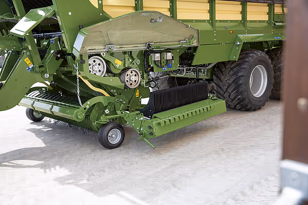 Krone ZX rundbalepresser montert på traktor viser hele maskinen fra siden med pressekammer og utløsningsmekanisme.