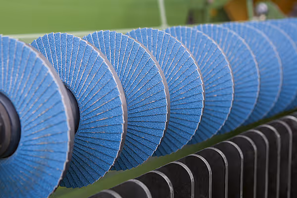 Detaljbilde av flere spiraltrommeltromler med blå plastlameller montert på rad på en høstmaskin.