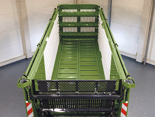 Innvendig oversikt av grønn KRONE ZX-vogn som viser høylaster-sidene med flere rekkjer av horisontale stenger og nettingverk i bunnen.