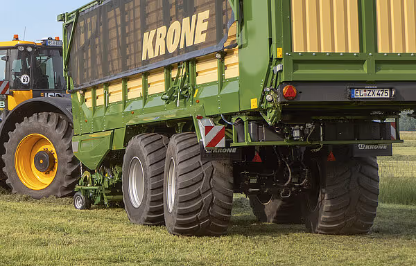 Bakansicht av grønn KRONE ZX vogn med traktor, viser doble hjul og rødt/hvitt varselskiltet på bakenden.