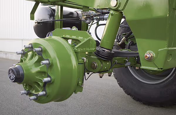 Detaljbilde av grønt bremseaggregat og hjulnav på vogn med hydrauliske slanger og mekaniske komponenter.