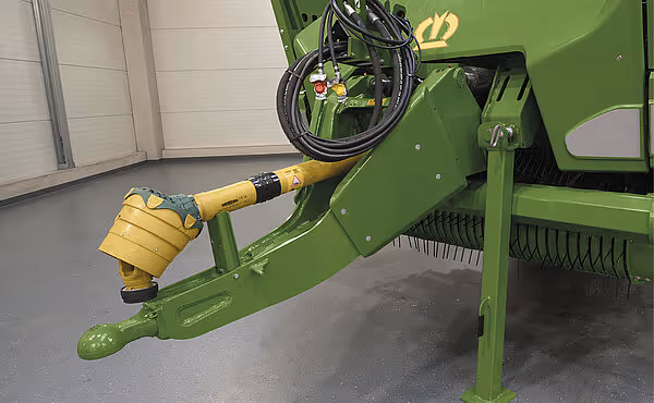 Nærbilde av hydraulisk sylinder med gul beskyttelseskappe montert på grønn KRONE rotorveihakker.