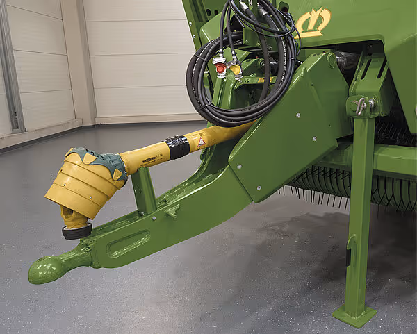 Gul hydraulisk sylinder med trykkluftkammer montert på grønn høstmaskinarm.