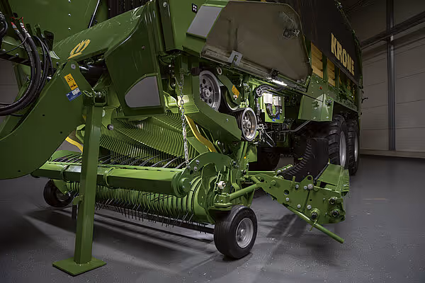 KRONE ZX høstmaskin montert under lastekar, viser skovlmekanisme og transportstilling i verksted.