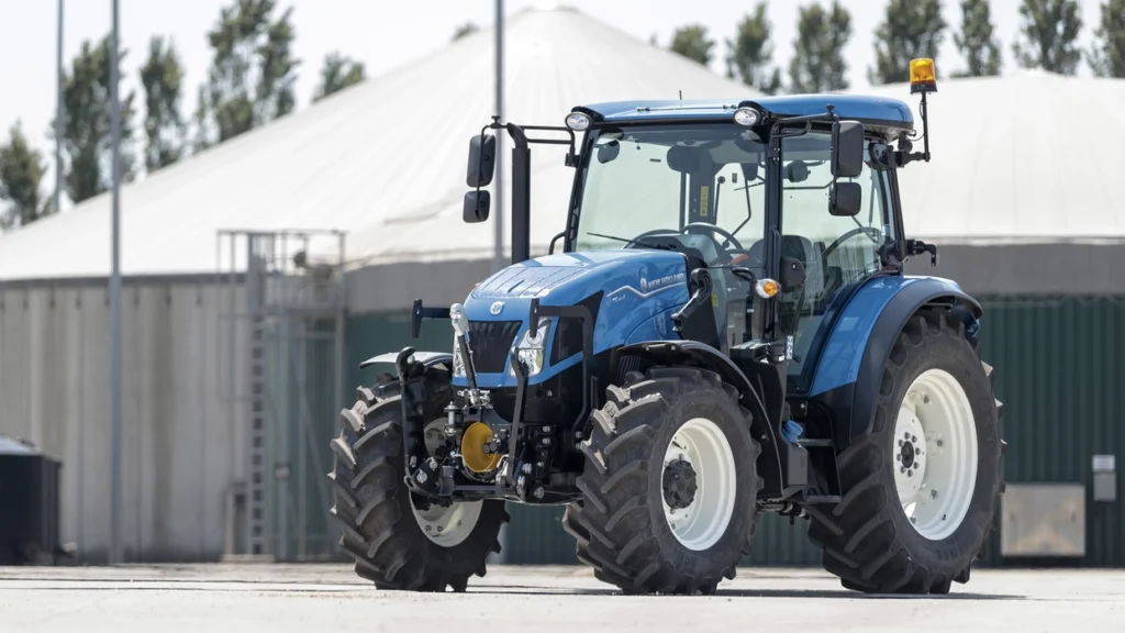 New Holland T5S-traktor parkert foran en landbruksbygning, med fokus på frontkoblingen og robuste dekk.