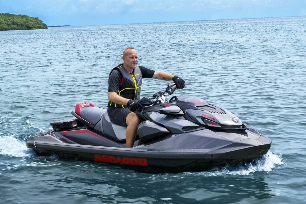 Nærbilde av en Sea-Doo GTR 230 med svart og blå design, sett fra siden på vannet.