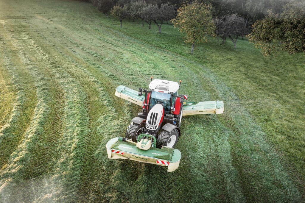 STEYR 6175 Impuls CVT traktor sett ovenfra ovenfra med Krone slåmaskin i aksjon på en eng.