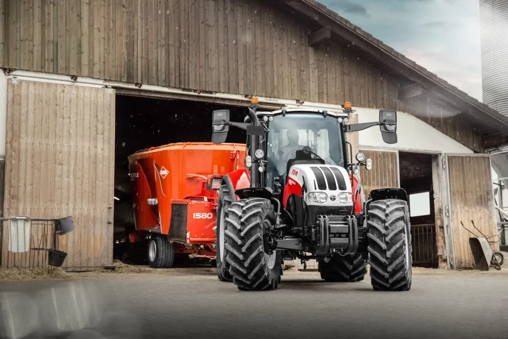 Steyr 4120 Multi-traktor foran et fjøs med en fôrblander festet bak.