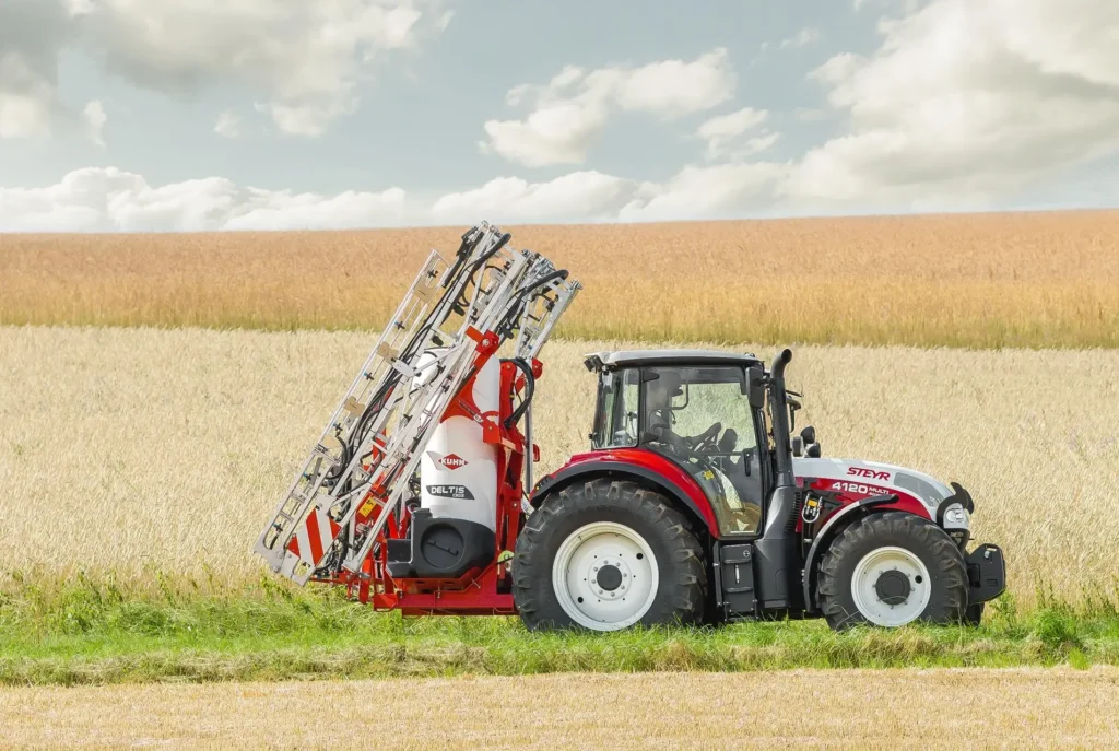 Steyr 4120 Multi-traktor med sprøyteutstyr i et kornfelt.